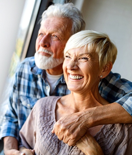 An older couple smiling and looking out the window