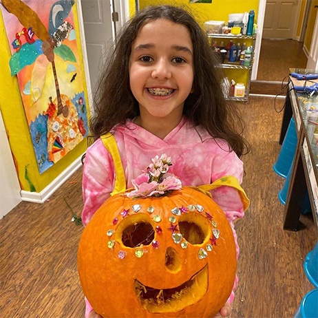 Little girl holding a decorated jack-o-lantern