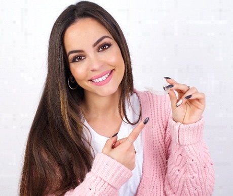 Pretty and happy young woman pointing at her SureSmile aligner
