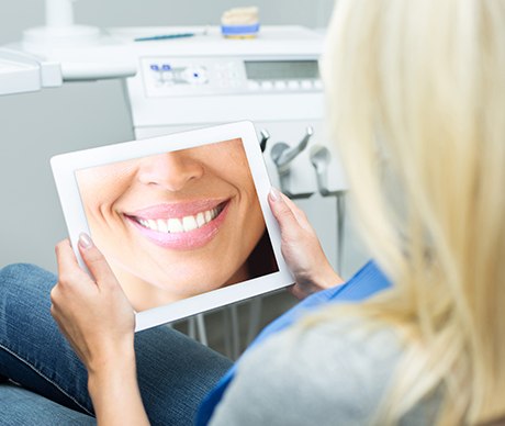 Woman looking at smile design on tablet computer