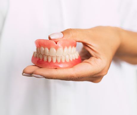 Man in white shirt holding full dentures in Vienna, VA