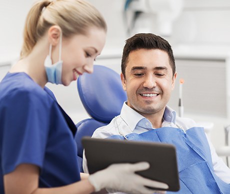 Dental assistant showing patient image on tablet