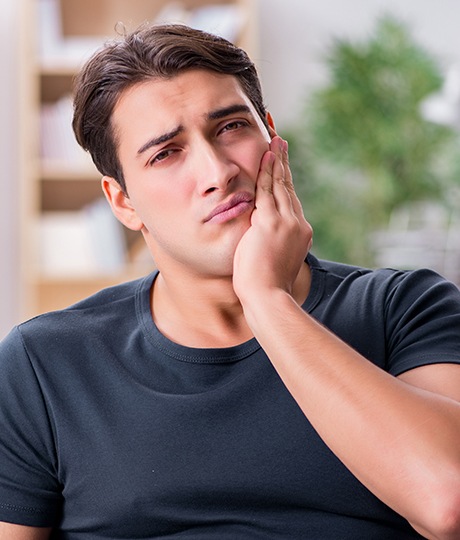 Man holding cheek in pain