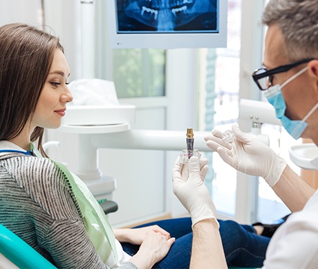 Dentist showing patient dental implant model