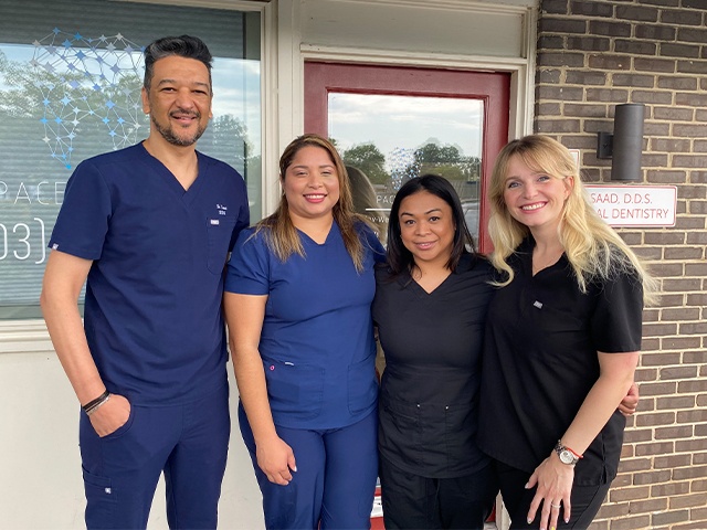 Dentist and dental team members outdoors with dentist giving peace sign in Vienna