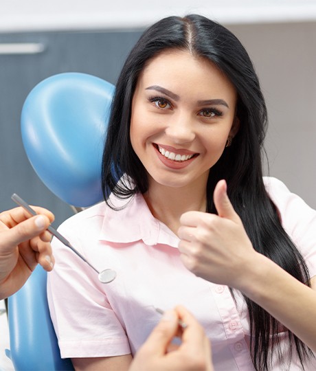 Woman in dental chair giving thumbs up