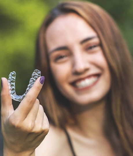 Happy young woman holding aligner for SureSmile in Vienna