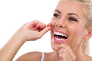 Woman with object stuck between teeth flossing.
