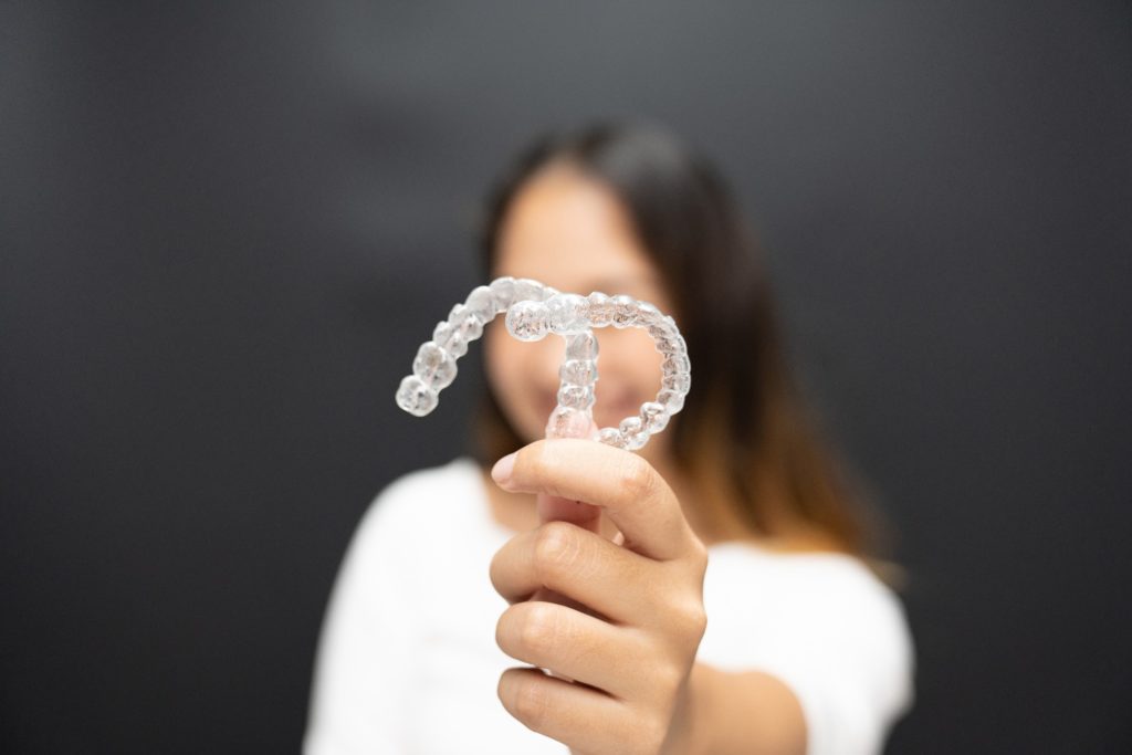 Patient holding up clear aligners for camera