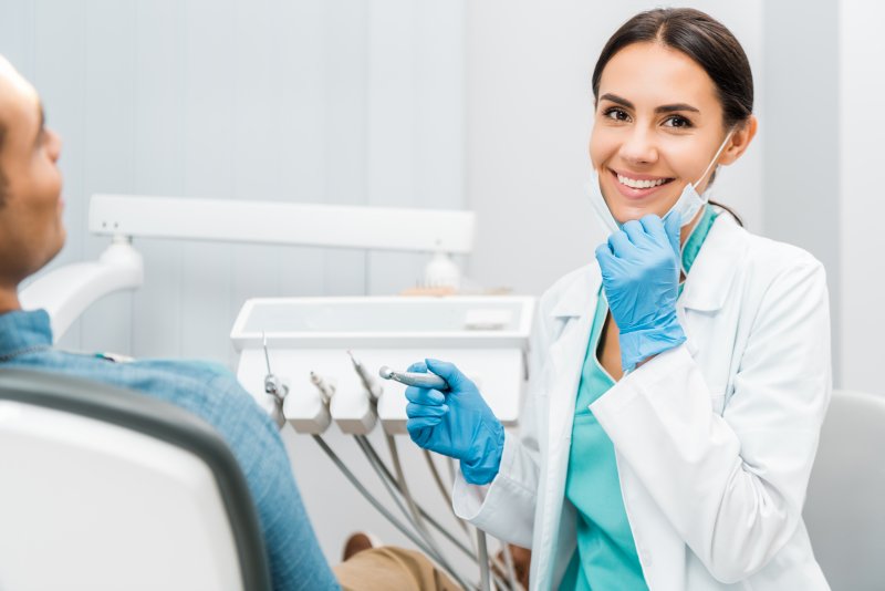 Dentist smiles during examination of patient.