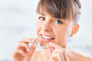 Young woman holding her Invisalign aligner