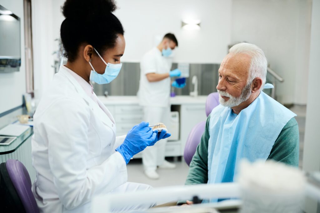 Dentist showing patient denture in treatment room